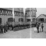 Lors d'une prise d'armes, des membres de la Hitlerjugend, au garde-à-vous devant deux cadres du N.S.F.K.
