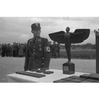 Deux officiers du N.S.F.K. : un Sturmbannführer et un Hauptsturmführer, encadrent une table où sont posés des trophées du N.S.F.K.