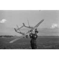 Un officier du Nationalistischen Flieger-Korps (N.S.F.K.) tient à bout de bras un modèle réduit d'avion, d'un genre particulier (bipoutre).