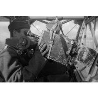 Un cameraman, membre de la 1re compagnie de propagande de l'armée de l'Air allemande (Luftwaffe Kriegsberichter Kompanie) filme le sol depuis le cockpit d'un Fi-156 Storch.