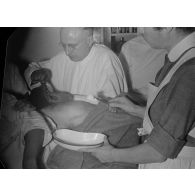 Un médecin fait une piqûre à un patient, assisté par une infirmière.