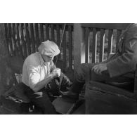 Un letton cire les bottes d'un aviateur allemand.