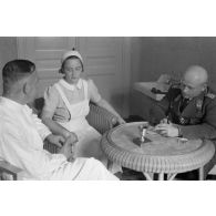 Un médecin et une infirmière discutent avec un capitaine (Hauptmann) de la Luftwaffe, peut-être un membre d'une compagnie de propagande.