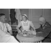 Un médecin et une infirmière discutent avec un capitaine (Hauptmann) de la Luftwaffe, peut-être un membre d'une compagnie de propagande.