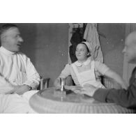 Un médecin et une infirmière discutent avec un capitaine (Hauptmann) de la Luftwaffe, peut-être un membre d'une compagnie de propagande.