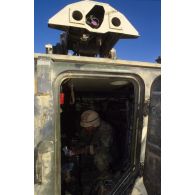 En ZDO (zone de déploiement opérationnel) Olive, la porte arrière ouverte d'un blindé M901 américain laisse deviner un soldat assis.