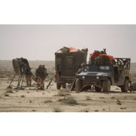 Des soldats américains manipulent une parabole près d'un shelter et d'un Hummer en ZDO (zone de déploiement opérationnel) Olive.