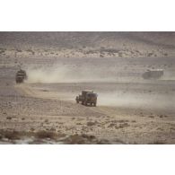 Des véhicules militaires français se déplacent dans le désert près de la frontière irako-saoudienne sur une piste.