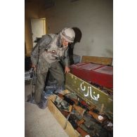 Un lieutenant du 3e RIMa (régiment d'infanterie de marine) casqué, vêtu de la tenue S-3P (survêtement de protection à port permanent) et d'un gilet pare-éclats, découvre une cache d'armes dans l'école d'Al Salman.