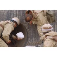 Des soldats inspectent une buse d'évacuation sous l'axe Texas.
