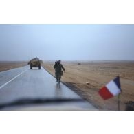 Sur l'axe Texas par un temps pluvieux, un brigadier caméraman de l'ECPA (Etablissement cinématographique et photographique des Armées), caméra sur l'épaule, revient vers le Peugeot P4 sur le capot avant duquel flotte un petit drapeau français.