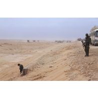 Sur un bas-côté de l'axe Texas emprunté par des convois de véhicules américains et français, un soldat français surveille un prisonnier irakien en contre-bas.