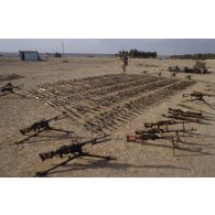 Des armes irakiennes récupérées, fusils d'assaut AK-47 ou AKM, et mitrailleuses PKMS et PKM de 7,62 mm, sont alignées au sol.