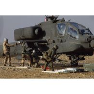 En ZDO (zone de déploiement opérationnel) Olive, des soldats ravitailllent en carburant et approvisionnent les paniers de roquettes de 70 mm d'un hélicoptère de combat américain Hughes-AH 64 Apache dans le désert.