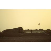 En zone Miramar, les tentes du campement, les levées de sable (merlon) et un canon de 20 mm sur camion TRM-2000 camouflé.