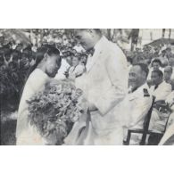 Une jeune fille offre des fleurs au président Hoach. [description provisoire]