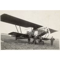 [Quatre hommes devant un avion biplan].