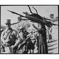 Une colonne de goumiers, avec à sa tête un sous-officier des Affaires Indigènes, est guidée dans le maquis par une paysanne.
