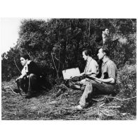 Un opérateur radio transmet un message sur un poste émetteur-récepteur (valise radio), sous la protection de résistants corses équipés de pistolets-mitrailleurs Sten Mk II.