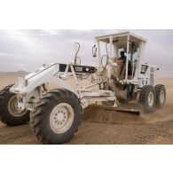 Un casque bleu tchadien réfectionne la piste du terrain d'aviation de Tessalit à bord d'une niveleuse.