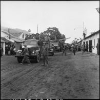 Montées sur camions Molotova, les troupes vietminh font leur entrée à Campha sous le regard de la population.