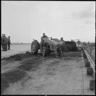 Aérodrome de Maison Blanche. Chantier de la nouvelle piste Est-Ouest en béton précontraint. Dépot du sable sur les couches bitumées.