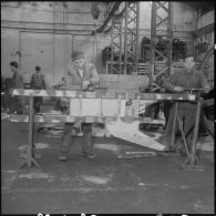 Oran. Ateliers et fonderies Célestin Ducros (AFCD). Ouvriers au travail sur un bâti support de chenilles.