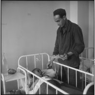 Tlemcen. Hôpital civil. Un homme donne à manger à un enfant.