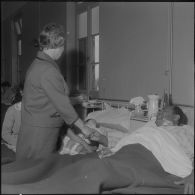 Alger. Hôpital Maillot. Madame Dumonte serrant la main d'un malade que sa jeune femme avec son enfant sont venus voir.