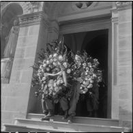 Des militaires, appartenant au 27e dragon, portant des gerbes de fleurs sur leurs épaules.