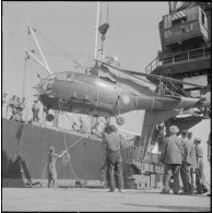 L'Alouette fin prête pour le voyage est soulevée par une grue qui la déposera dans la cale du bateau.