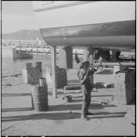 Mers el-Kébir. Les ouvriers repeignent la coque de la vedette côtière P755  à l'aide de panneaux et de rouleaux.