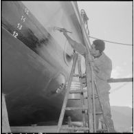 Mers el-Kébir. Les ouvriers repeignent la coque de la vedette côtière P755 à l'aide de panneaux et de rouleaux.