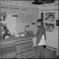 Inauguration de la foire exposition d'Oran. Un jeune vendeur de journaux devant une exposition de réalisations de jeunes apprentis, au pavillon de l'orientation professionnelle.