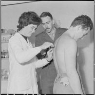 Attention à la piqûre. Sous l'oeil de l'infirmier, cette membre des équipes médico-sociales itinérantes (EMSI)  fait une piqûre.