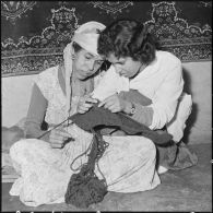 Une membre des équipes médico-sociales itinérantes (EMSI) montre à une femme comment tricoter.