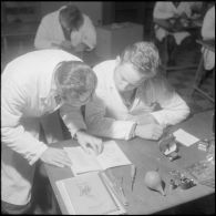 Camp de L'Alma (camp Bonvalot). Centre d'instruction du service du matériel n°3 (CISM n° 3). Un soldat travaillant sur des pièces en cours d'optique en suivant les conseils d'instructeur.