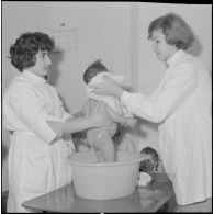 Aïn Temouchent. Une membre de l'équipe médico-sociale itinérante montre à une mère comment faire la toilette de son bébé.