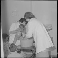 Aïn Temouchent. Une membre de l'équipe médico-sociale itinérante montre à une mère comment faire la toilette de son bébé.