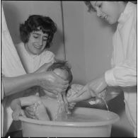 Aïn Temouchent. Une membre de l'équipe médico-sociale itinérante montre à une mère comment faire la toilette de son bébé.