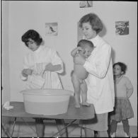 Aïn Temouchent. Une membre de l'équipe médico-sociale itinérante montre à une mère comment faire la toilette de son bébé.