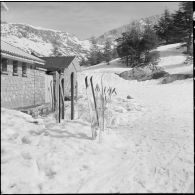 Tikdja. 22e bataillon de chasseurs alpins (BCA). Des chasseurs alpins ont plantés leurs skis et leurs bâtons à l'entrée d'une maison.