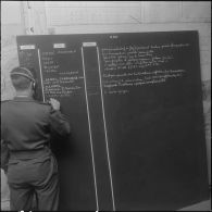 La Reghaïa. Salle opérationnelle des transmissions. Un soldat note des renseignements sur un tableau.