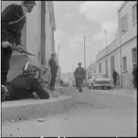 Oran. Fouilles et récupérations d'armes de l'Organisation armée secrète (OAS). Des gendarmes mobiles en position de tir dans une rue.