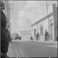 Oran. Fouilles et récupérations d'armes de l'Organisation armée secrète (OAS). Des gendarmes mobiles dans une rue et à bord d'une automitrailleuse Light armored car M8.
