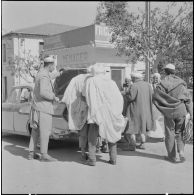 Fondouk. Des hommes devant le coffre d'une voiture ouverte.