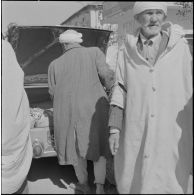 Fondouk. Des hommes devant le coffre d'une voiture ouverte.
