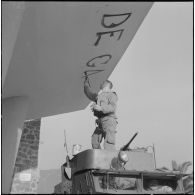 Oran. Mise en place des troupes sur les terrasses. Un soldat écrit "Vive De Gaulle" à la peinture, à l'entrée d'un immeuble.