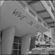 Oran. Mise en place des troupes sur les terrasses. Un soldat écrit "Vive De Gaulle" à la peinture, à l'entrée d'un immeuble.