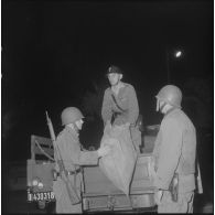 Oran. Mise en place des troupes sur les terrasses. Des soldats sortent des sacs d'un camion, en bas d'un immeuble.